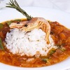 ルイジアナのクレオール風エビのトマト煮込み／シュリンプ・クレオール　フランス，スペイン，アフリカ，西インド諸島の文化が交わる港町ニューオーリンズ生まれ．Creole（クレオール）とは，こうした混血・混文化社会で育った人々とその食文化を指します．  「フランスの煮込み＋スペインのソフリート（野菜炒め）＋西インド諸島のスパイス感＋南部の米料理」という文化的融合から産まれたこの料理では，エビは風味豊かなトマトソースで煮込まれ，白米の上に盛り付けて提供されるのが一般的．