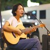 ストリートライブでギターを弾き語りする女性歌手