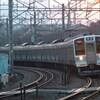 夕陽をバックにカーブを通過する211系電車