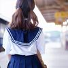 女子高校生が制服の短いスカートをおさえて階段を上っている