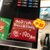 ローソンでGODIVAのチョコレートカフェが半額で売ってて、半額表示さえオシャレだったのに、なぜか黄色と赤のシールが貼られていて、台無しになっている図。そんなに在庫が余ったのだろうか？