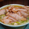 新橋ニューともちんラーメン 川崎駅前店 - 初訪問。チャーシュー麺。表面を覆い尽くすチャーシューのボリュームに否が応でも上がる。しっとり柔らかくてうんま。薄いが故に贅沢に一気に行くとミルフィーユ。ほのかなしょっぱさと重すぎないけど確かにオイリーでしっかりと重心が安定したスープは、恐らくほとんどの人がイメージする中華そばの味。朝5時までと川崎エリアのラーメンの最後の砦として頼しすぎる。