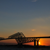 東京ゲートブリッジの向こうへ沈む夕日を撮る