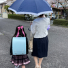 そぼ降る雨の中を水色のランドセルで臨む小学校の入学式